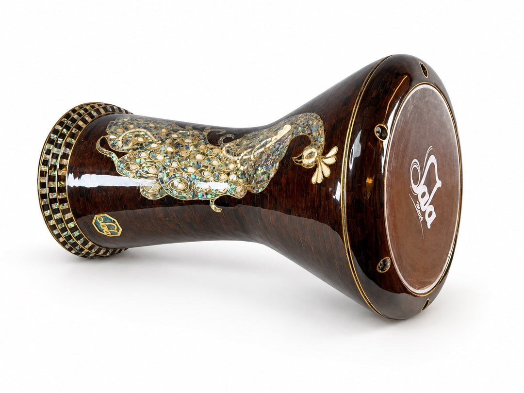 Sala Amber Peacock Sombaty دربوكة على جانبها، تظهر رأس الطبلة الذي يحمل العلامة التجارية Sala وشكل الطاووس الشاحب على خلفية فسيفساء بنية كهرمانية داكنة.